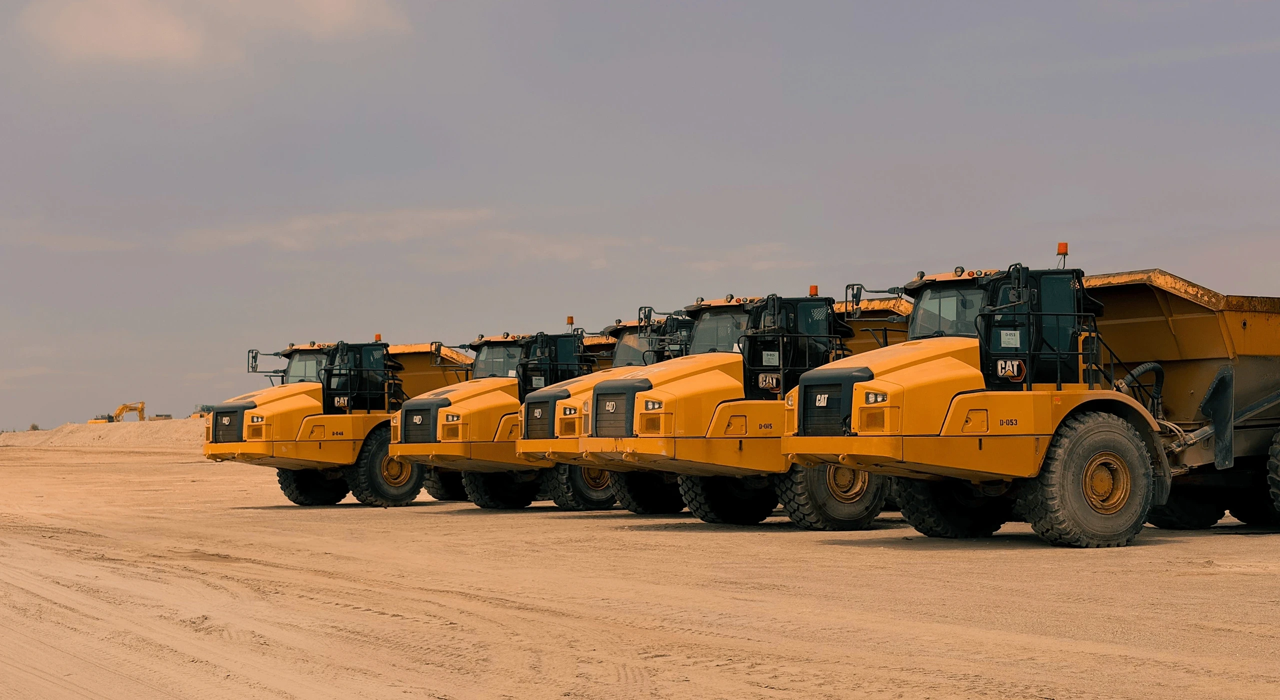 Row of heavy-duty dump trucks parked in a construction site.