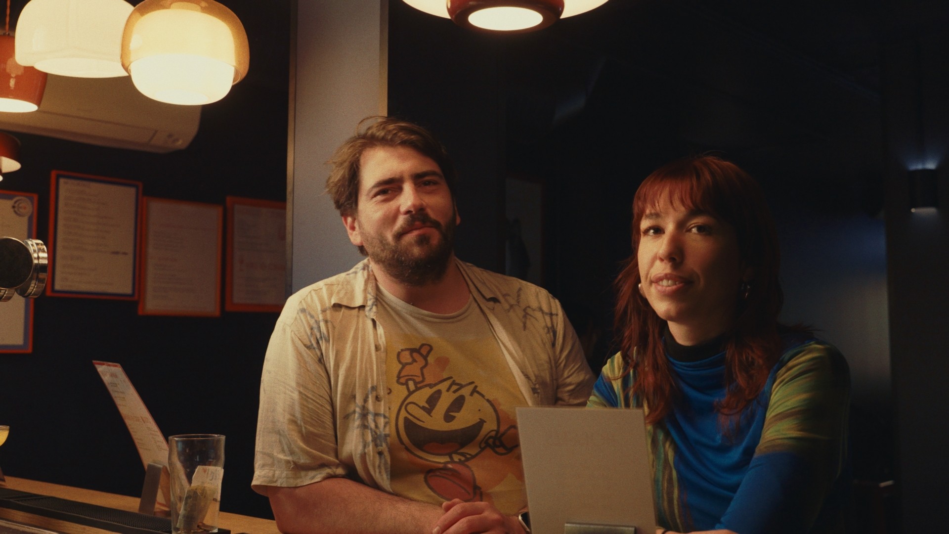 Deux clients posent au comptoir de Les Petites Flèches, ambiance chaleureuse en soirée.