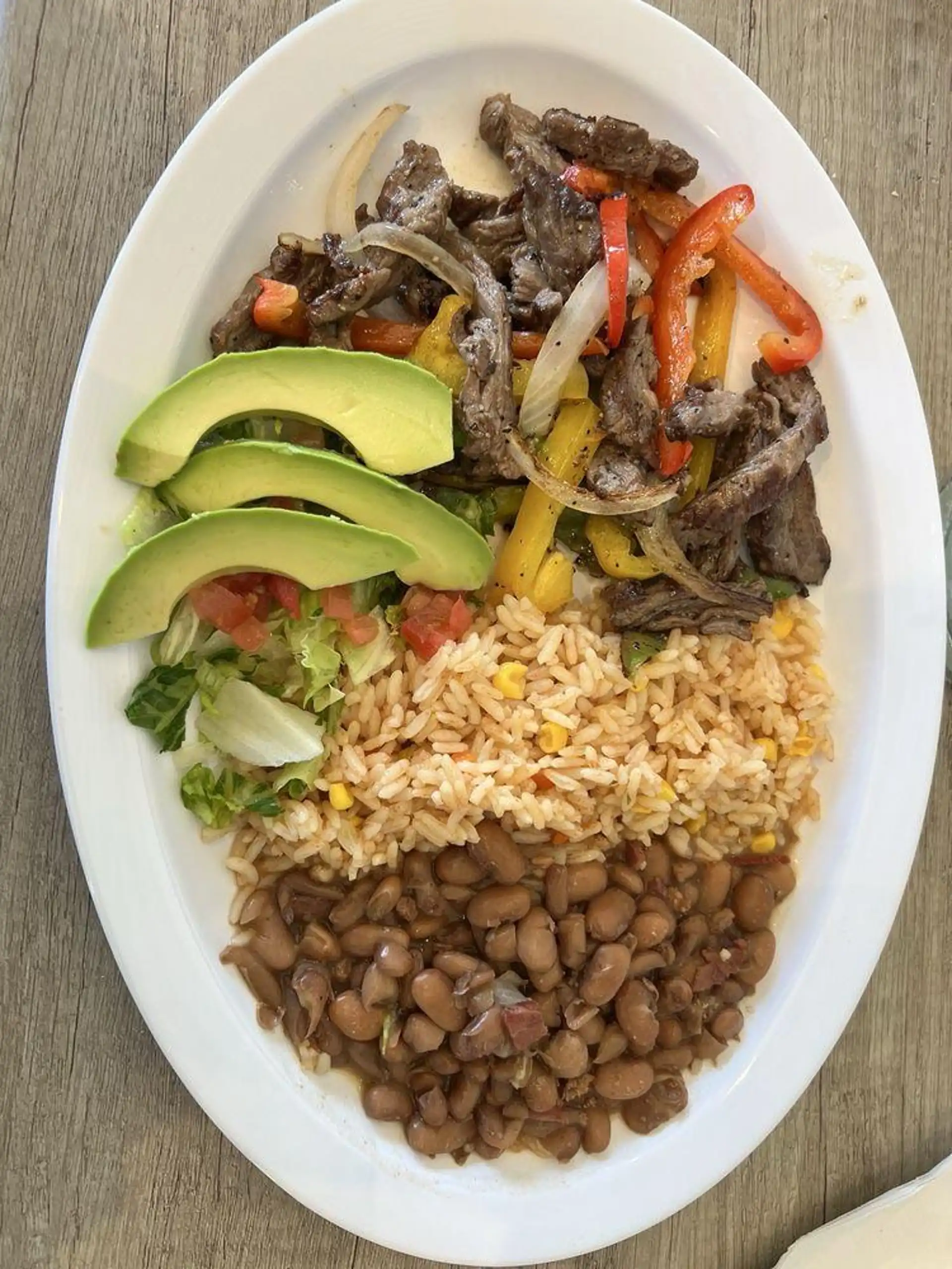 Grilled steak with sautéed onions, bell peppers, and tomatoes, typically served with rice, beans, guacamole, sour cream, pico de gallo, and warm tortillas. Description generated by DoorDash using AI