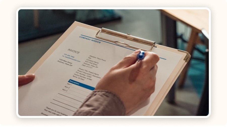 Hand holding a clipboard with a printed invoice