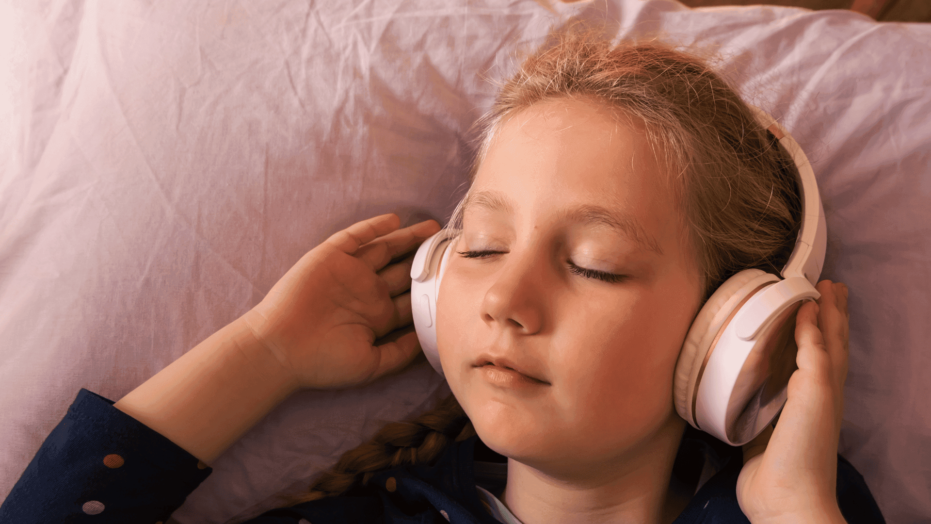 A young girl lying with her head on a pillow, eyes closed, listening to HushAway®’s Sound Sanctuary.