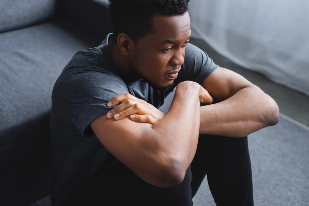 Depressed African American man sitting with arms folded