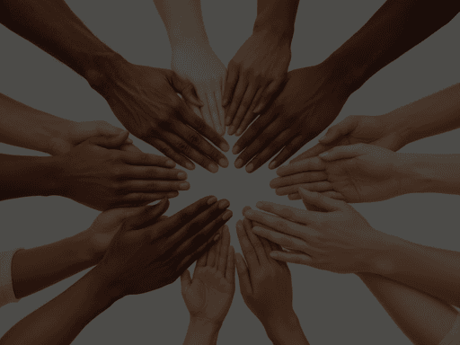 Many hands of different skin tones are placed together in a circle.