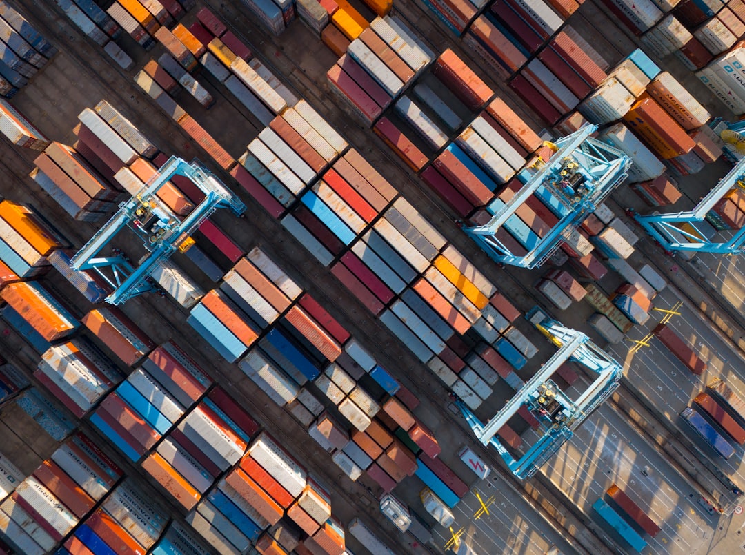 logistics manager looking at a large tablet with colorful data visualizations, charts, and maps, clean office setting, blurred trucks in the window