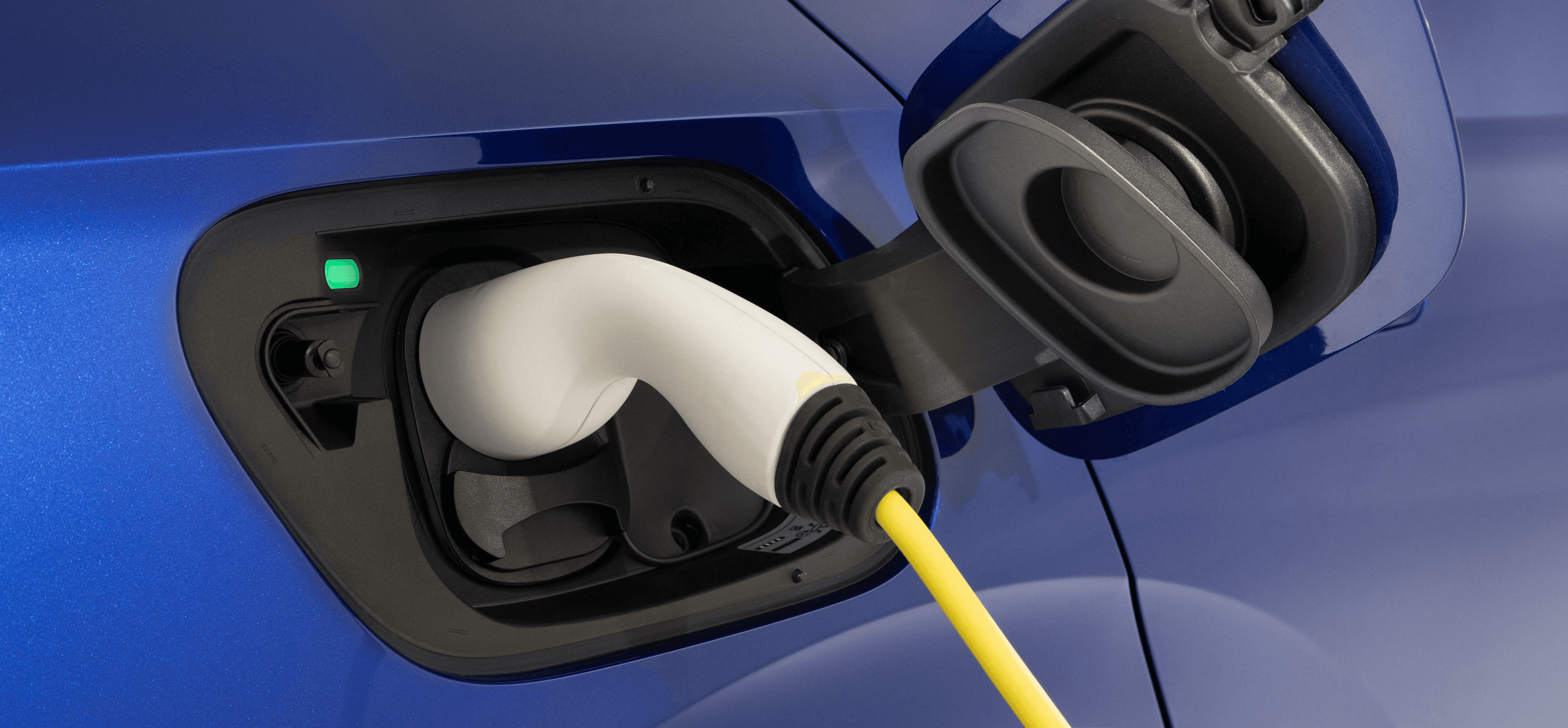 Port de recharge d’une Volkswagen électrique, gros plan sur la prise branchée et la trappe ouverte