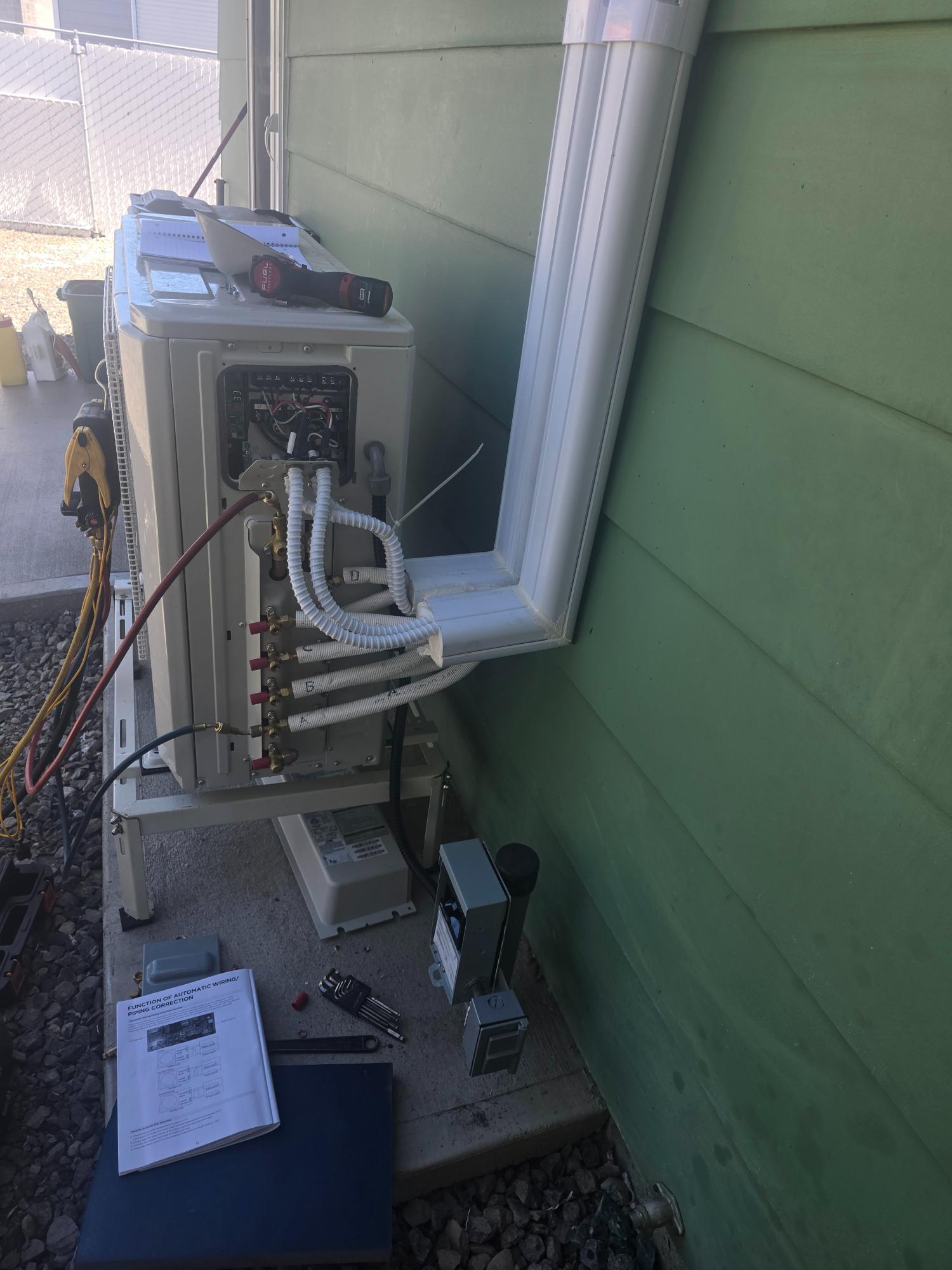 Outdoor mini split system being wired and installed.