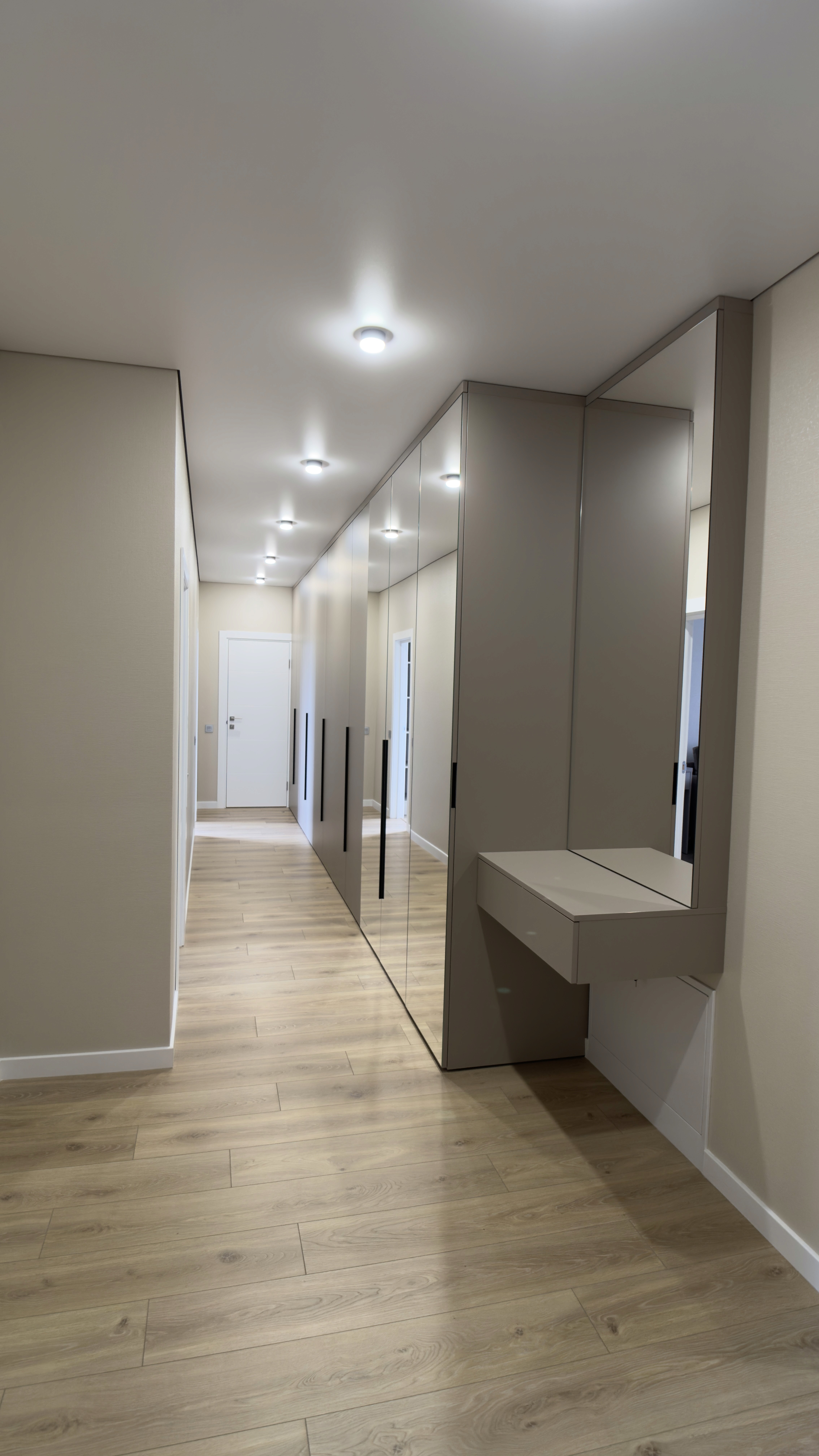 Довгий коридор із дзеркальними шафами, глянцевими фасадами та вбудованим освітленням