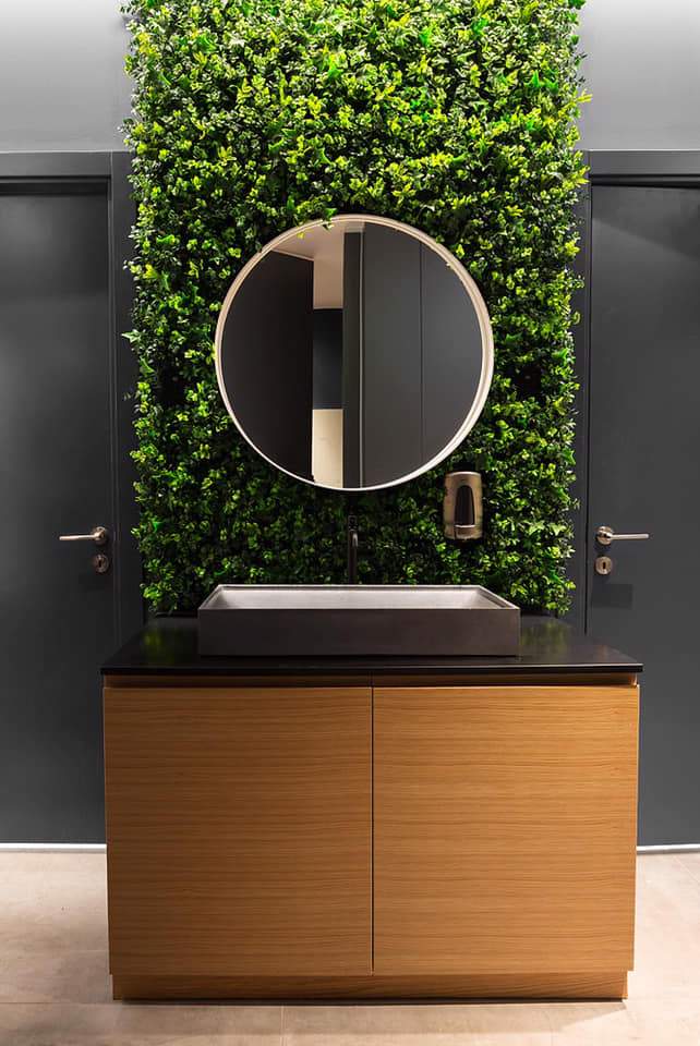 דלפק קבלה מעוצב עם אלמנט מיתוג ייחודי על רקע קיר אבן – עיצוב קונספטואלי למשרדים