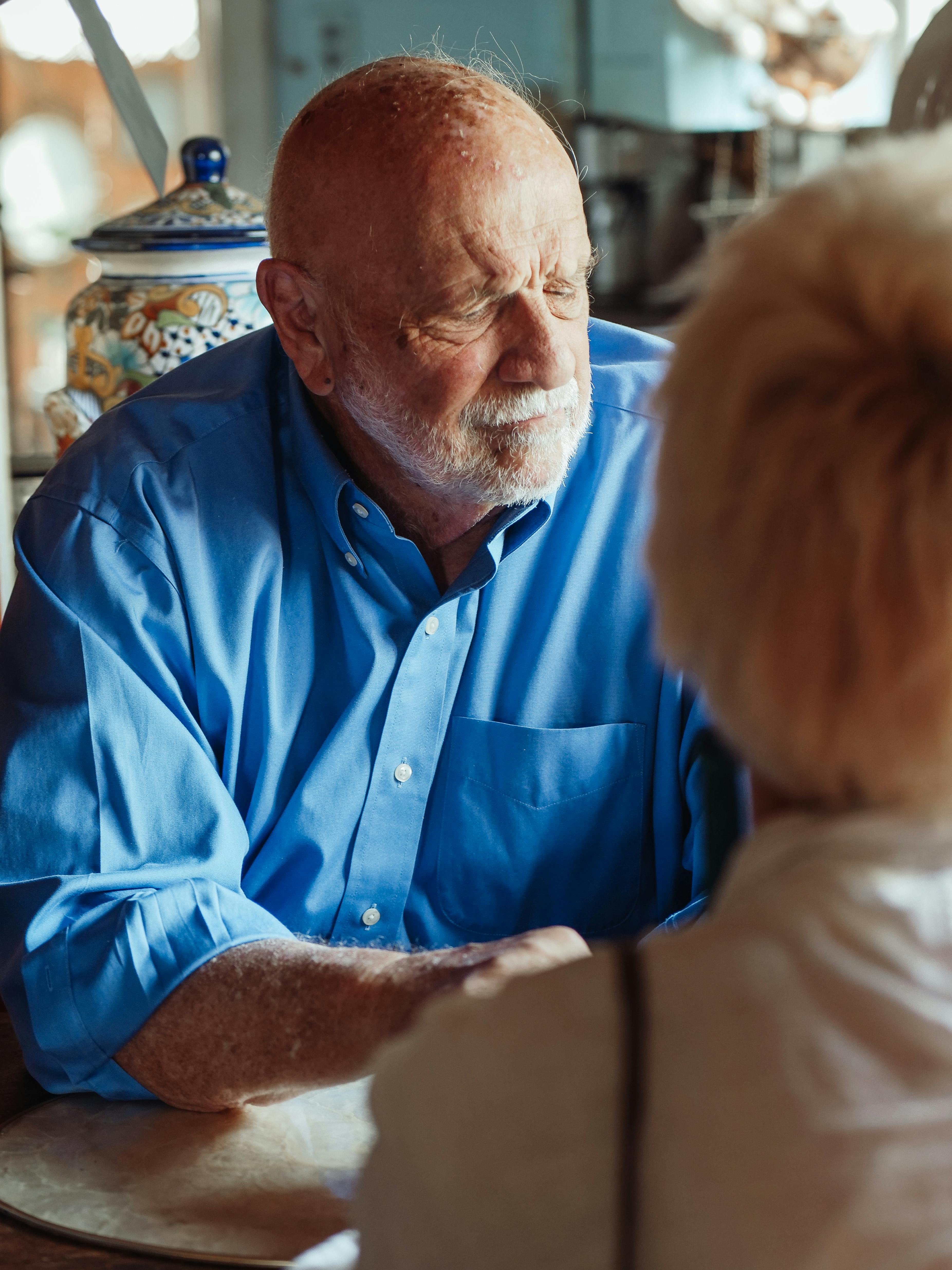 Support worker comforting senior man with dementia during calm home visit.
