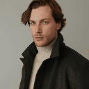 A man dressed in a black coat and turtle neck sweater, showcasing a stylish and sophisticated look.