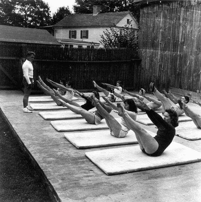 Photographie ancienne en noir et blanc d’un cours de yoga sur tapis