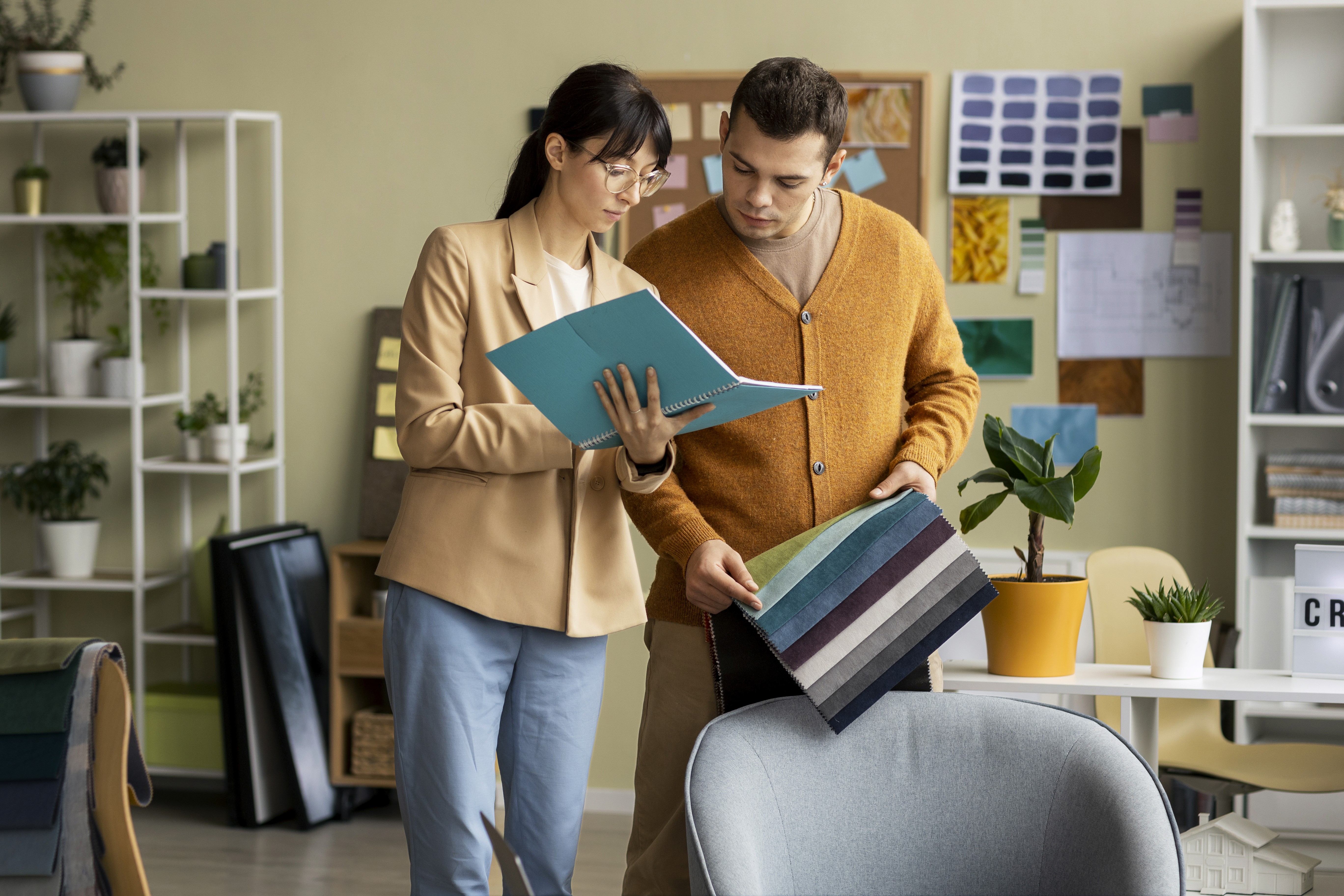 Designers collaborating in a creative workspace, reviewing materials and color samples while planning interior or visual design concepts together.