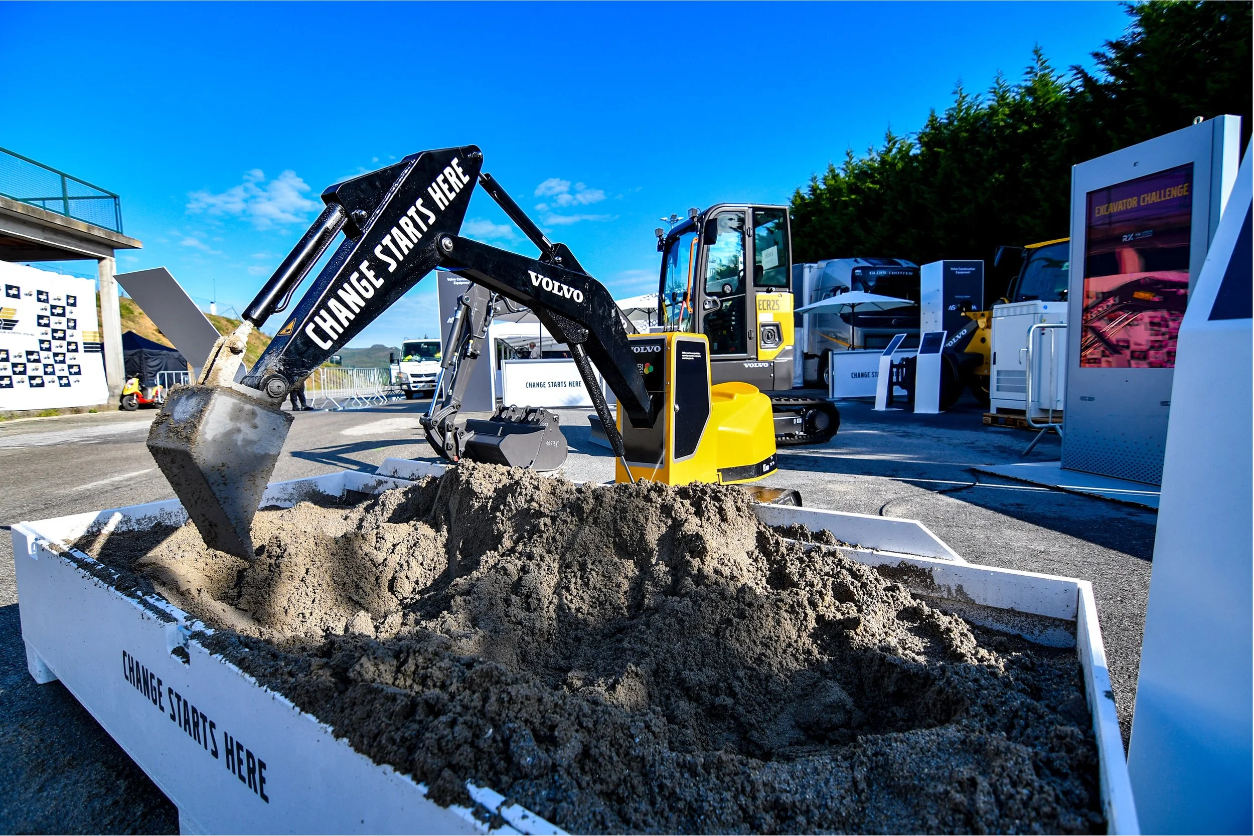 En grävmaskin på ett evenemang som gräver i en visningssandlåda