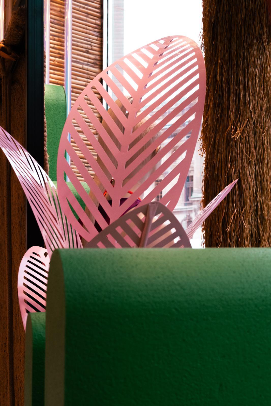 Détail de feuilles décoratives roses en métal et d'un cactus vert dans la vitrine Undiz.