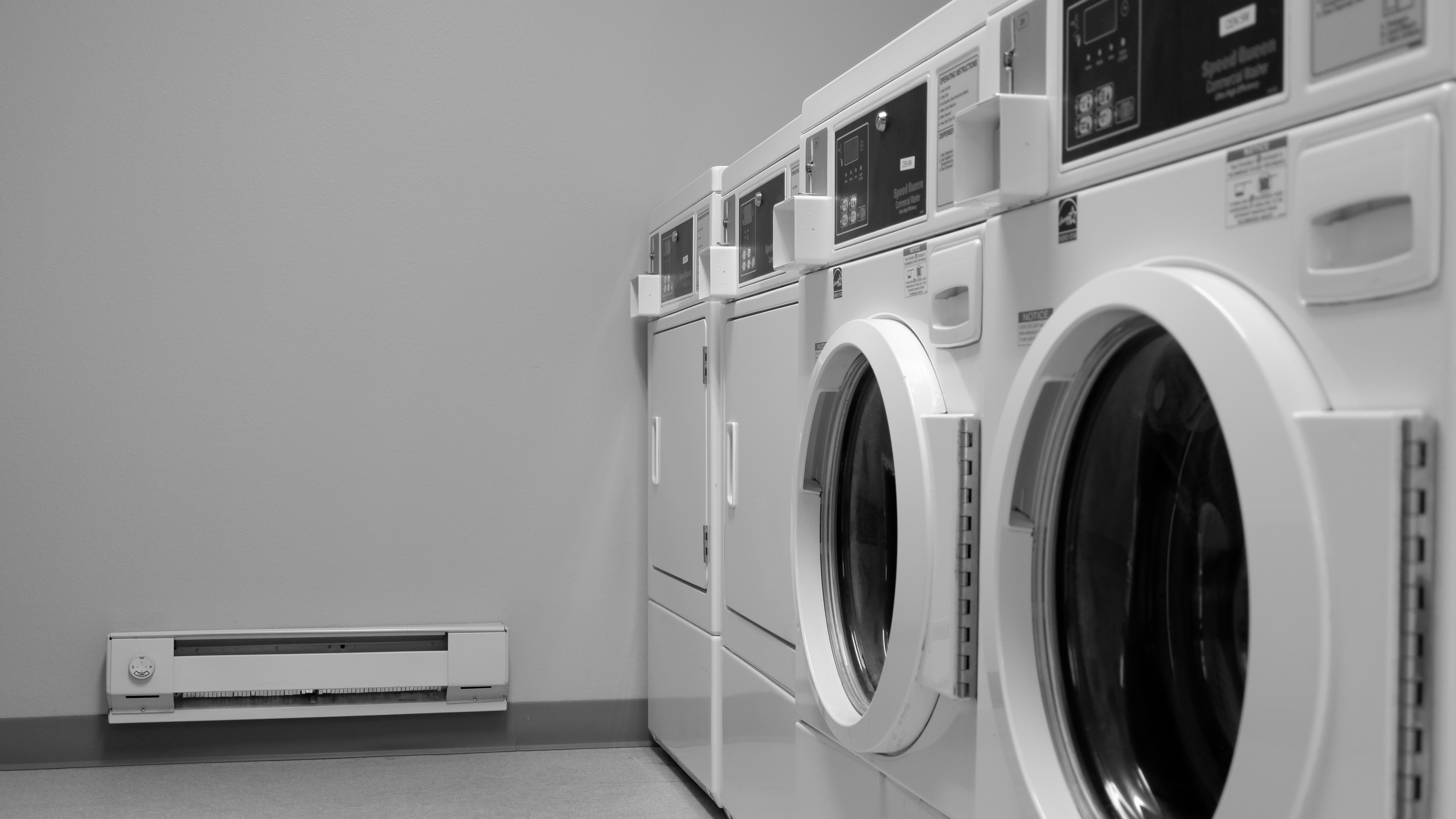 A clean row of white front-load washers against a gray wall