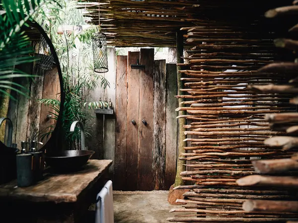 Deluxe Tent at Nômade Tulum highlighting rustic shower, sink, and large mirror with jungle-style decor.