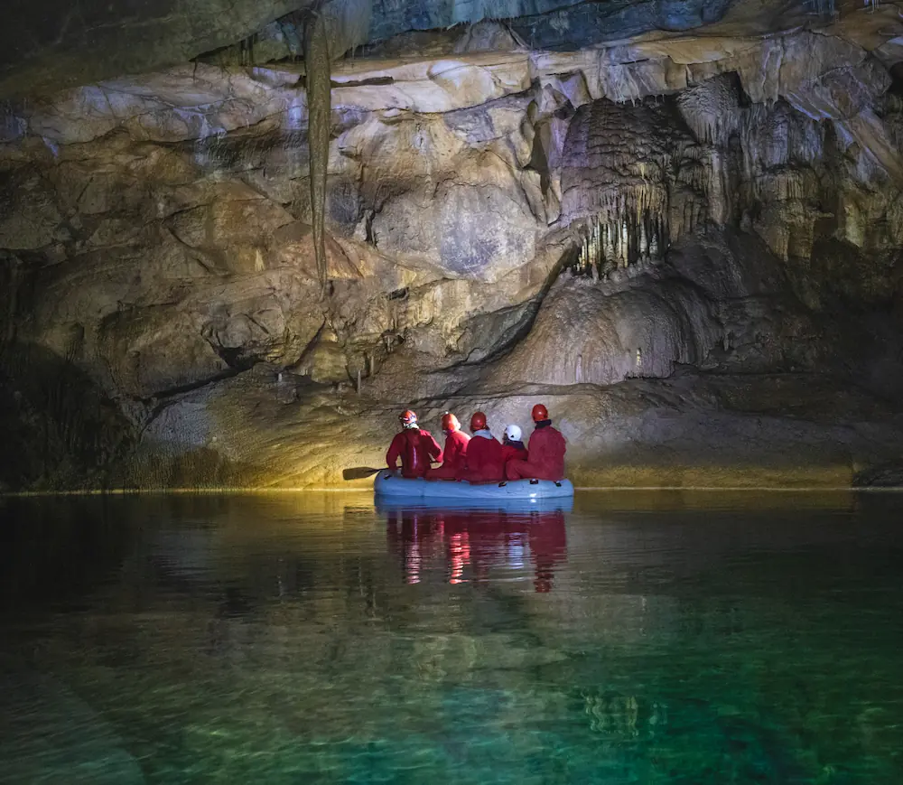 A group of cave explorers on a small boat ona calm water inside the Križna Cave, Slovenia