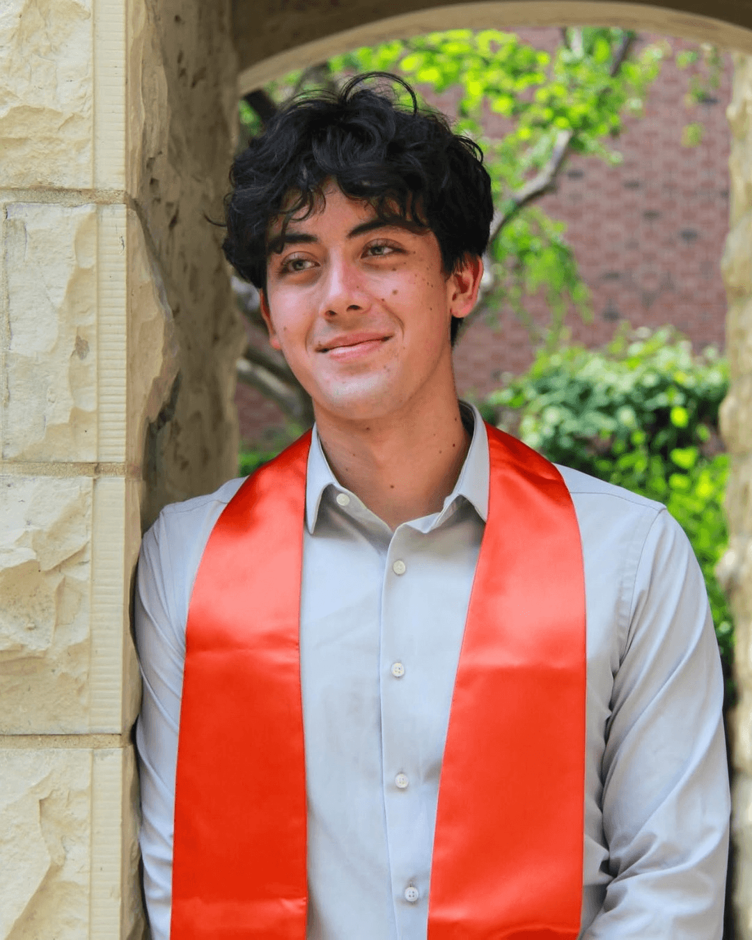 Smiling person with curly hair, wearing a black shirt, against a warm, dark background.