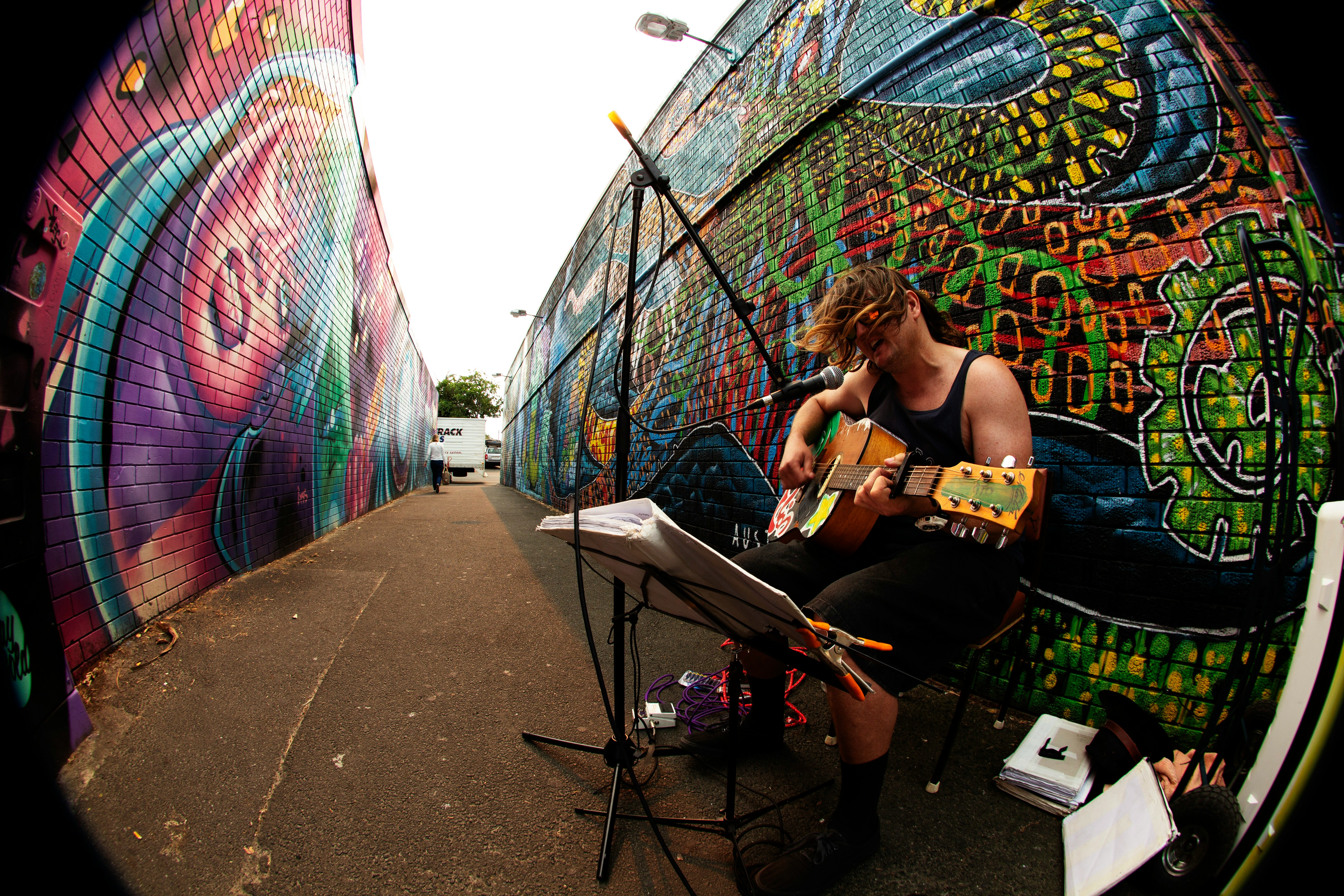 man in black t-shirt playing guitar sitting on chair