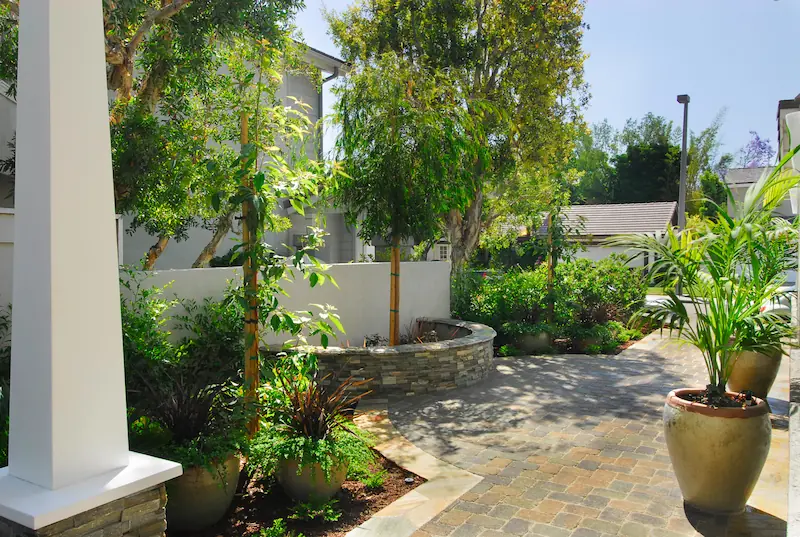 Shaded garden walkway with flagstones, green foliage, and white pillars at Irvine Transitional Modern. Photo by Chris Darnall.