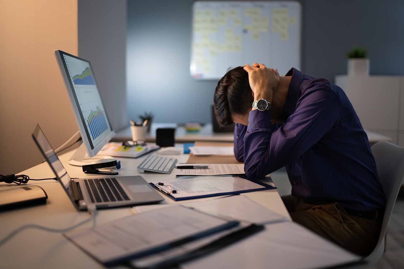 Empleado con signos de estrés frente al computador en oficina corporativa