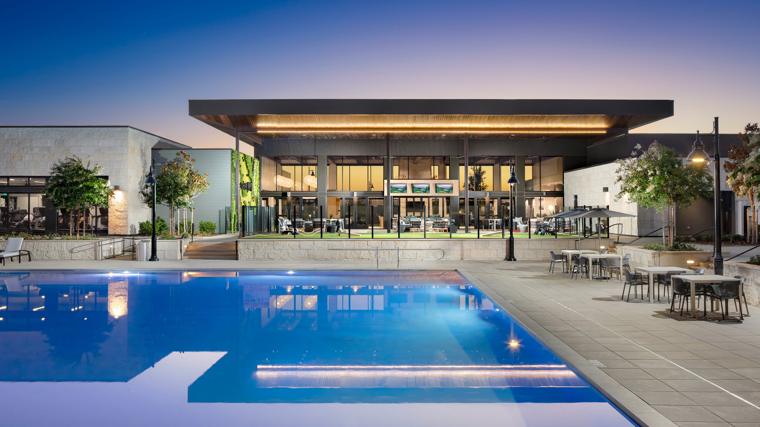 Modern clubhouse with pool at sunset.