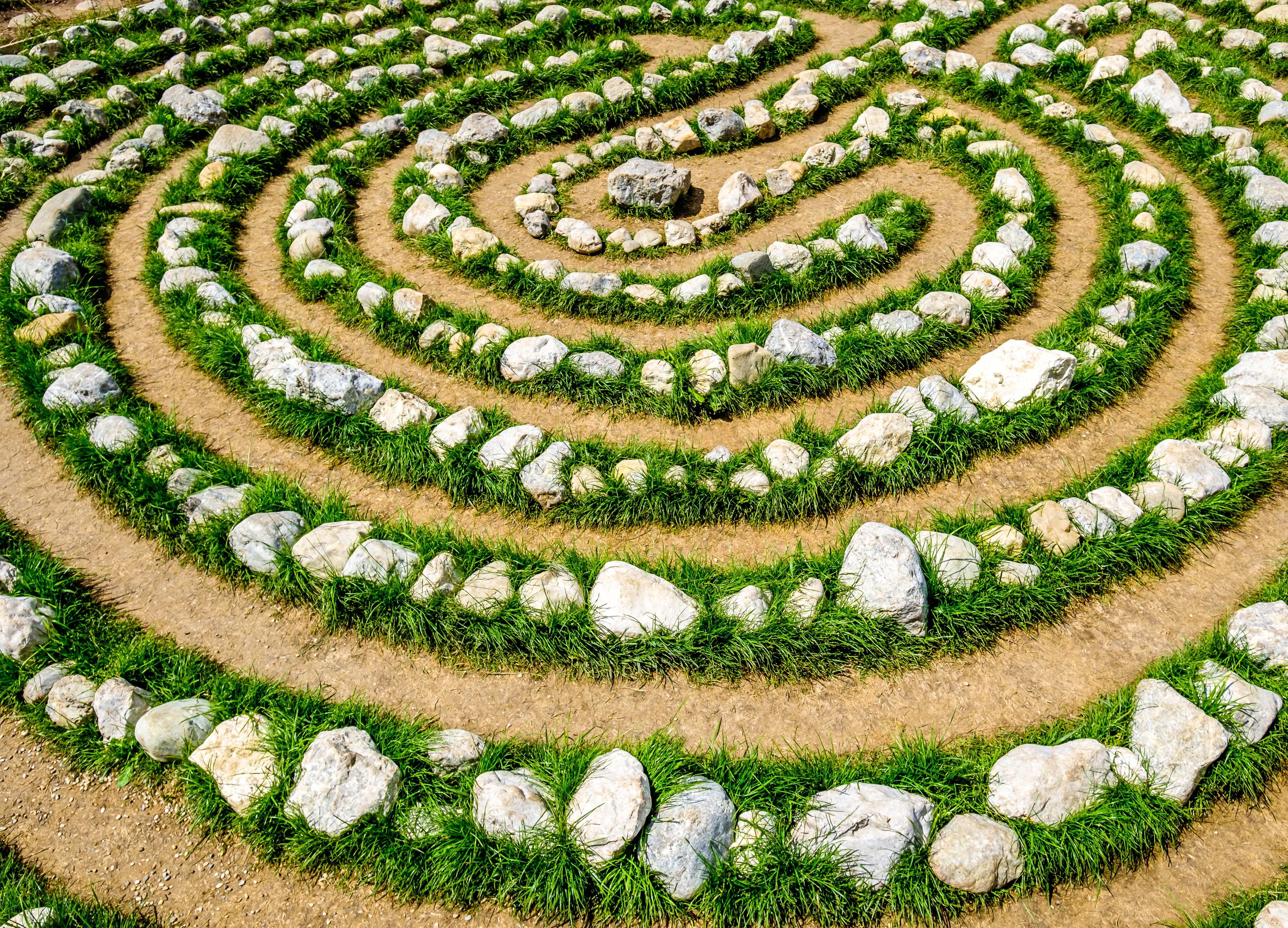 A top-down detailed view of a circular walking labyrinth constructed with white stones embedded in lush green moss.