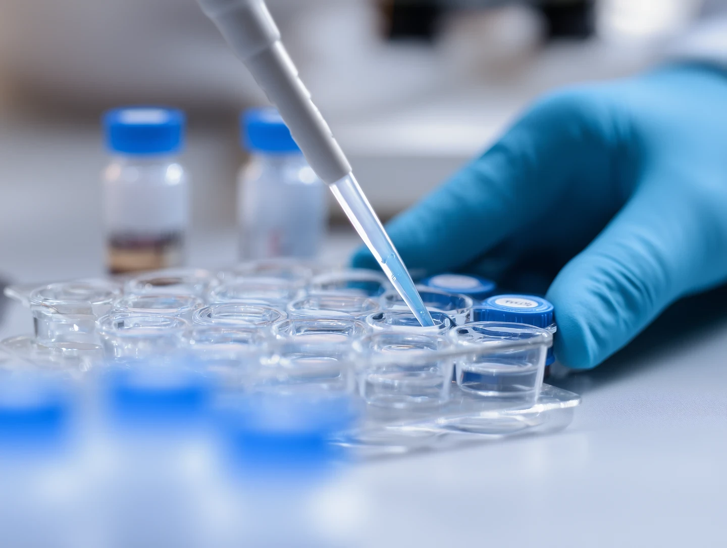 A pippette containing a small solution moving from one test tube container to another. In the manner of adding a reagent to a solution