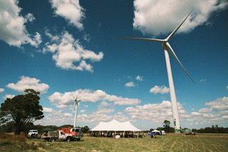 Wind turbines and event tent in a grassy field.