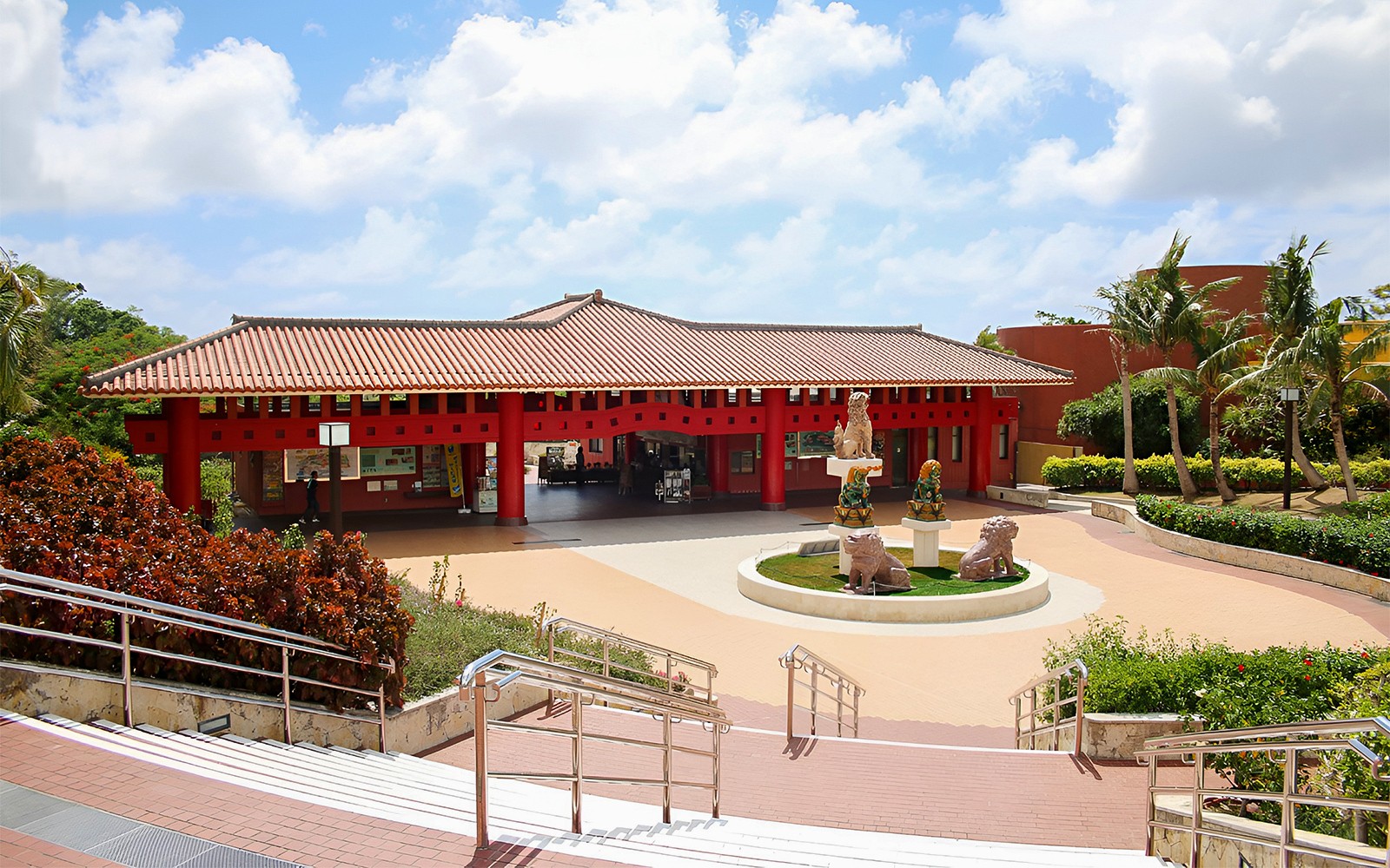 Είσοδος του Okinawa World με παραδοσιακή κόκκινη αρχιτεκτονική και αγάλματα λιονταριών.