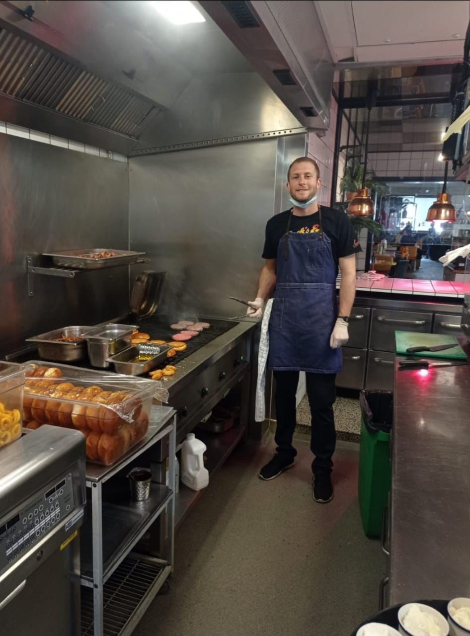a man in a kitchen cooking burgers