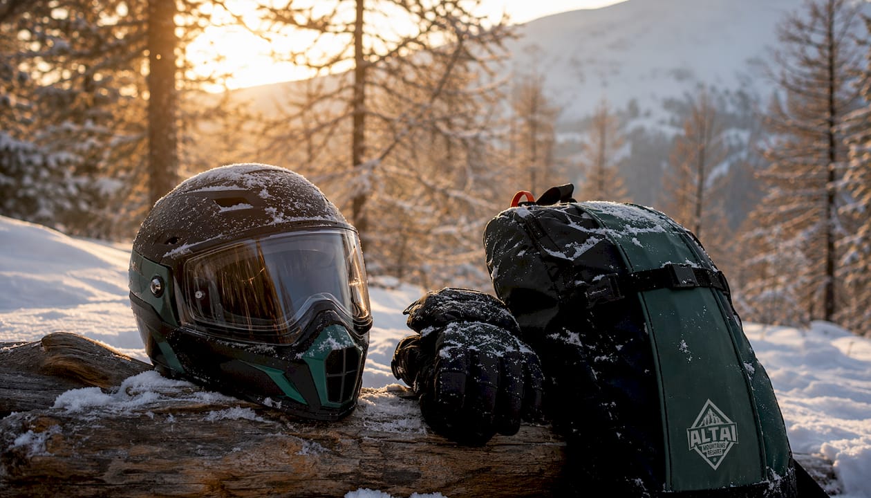 Snowmobile safety gear arranged on a bench in a snowy forest