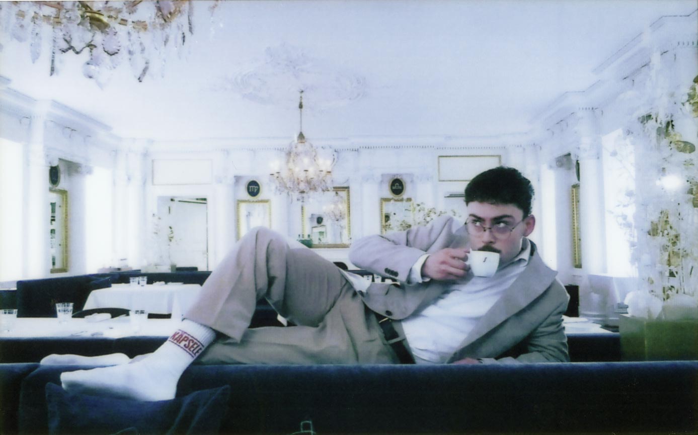 Jonathan Miehlich drinking a coffe, laying weirdly on the back of a couch in Stuttgart's two star restaurant Speisemeisterei