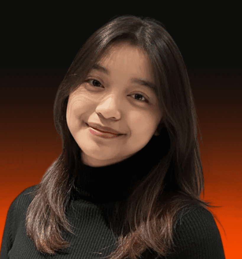 A man with curly hair smiling in a field of yellow flowers at sunset.