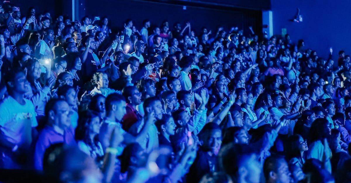 A packed crowd enjoys a live concert, bathed in dynamic blue lighting, capturing excitement.