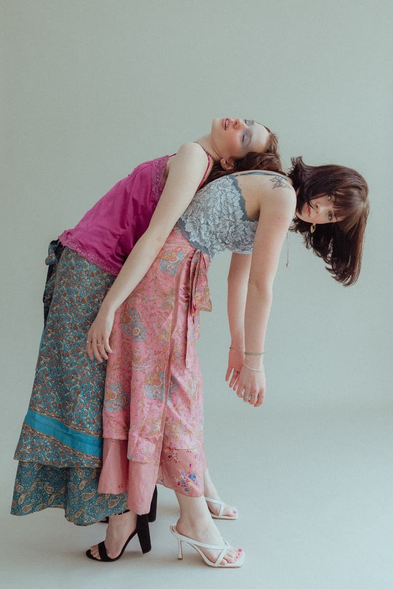 Models leaning on each other, one in pink and the other in blue lace, during a creative shoot at Revelator Studio, a natural light studio in Shreveport.