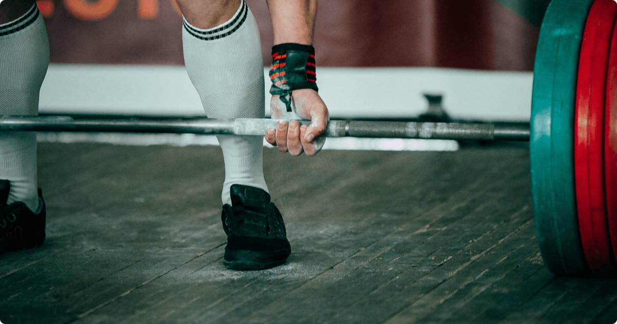 Close-up of a person performing a deadlift, gripping a barbell with both hands