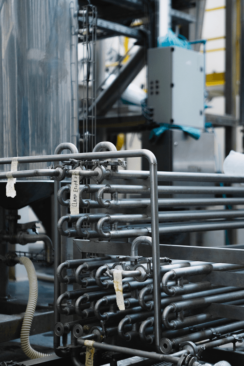 Compact stainless steel heat exchanger with multiple pipes in an industrial plant.