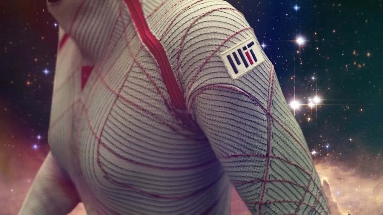 A futuristic spacesuit with a textured design and red accents, featuring the MIT logo on the sleeve, set against a starry galaxy background.