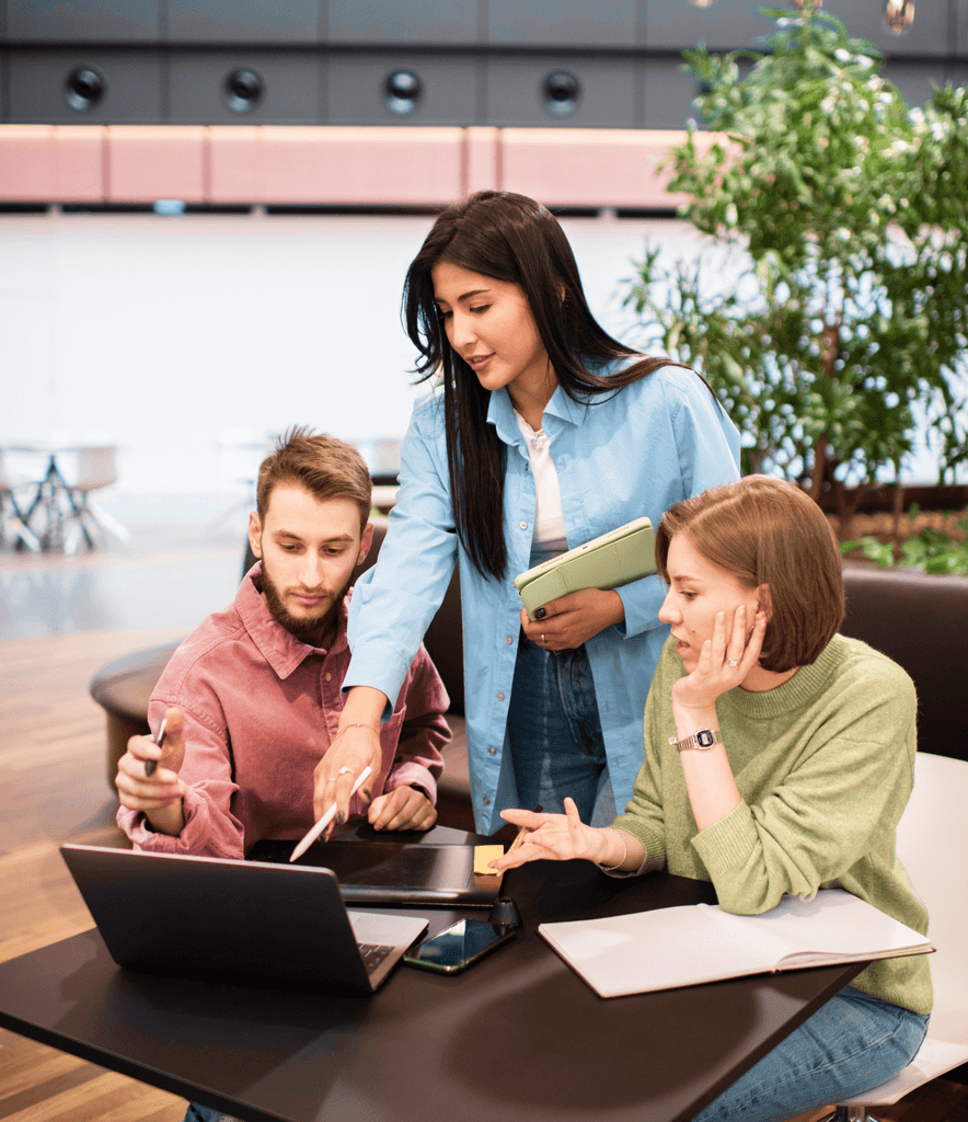 Three people collaborating around a laptop.