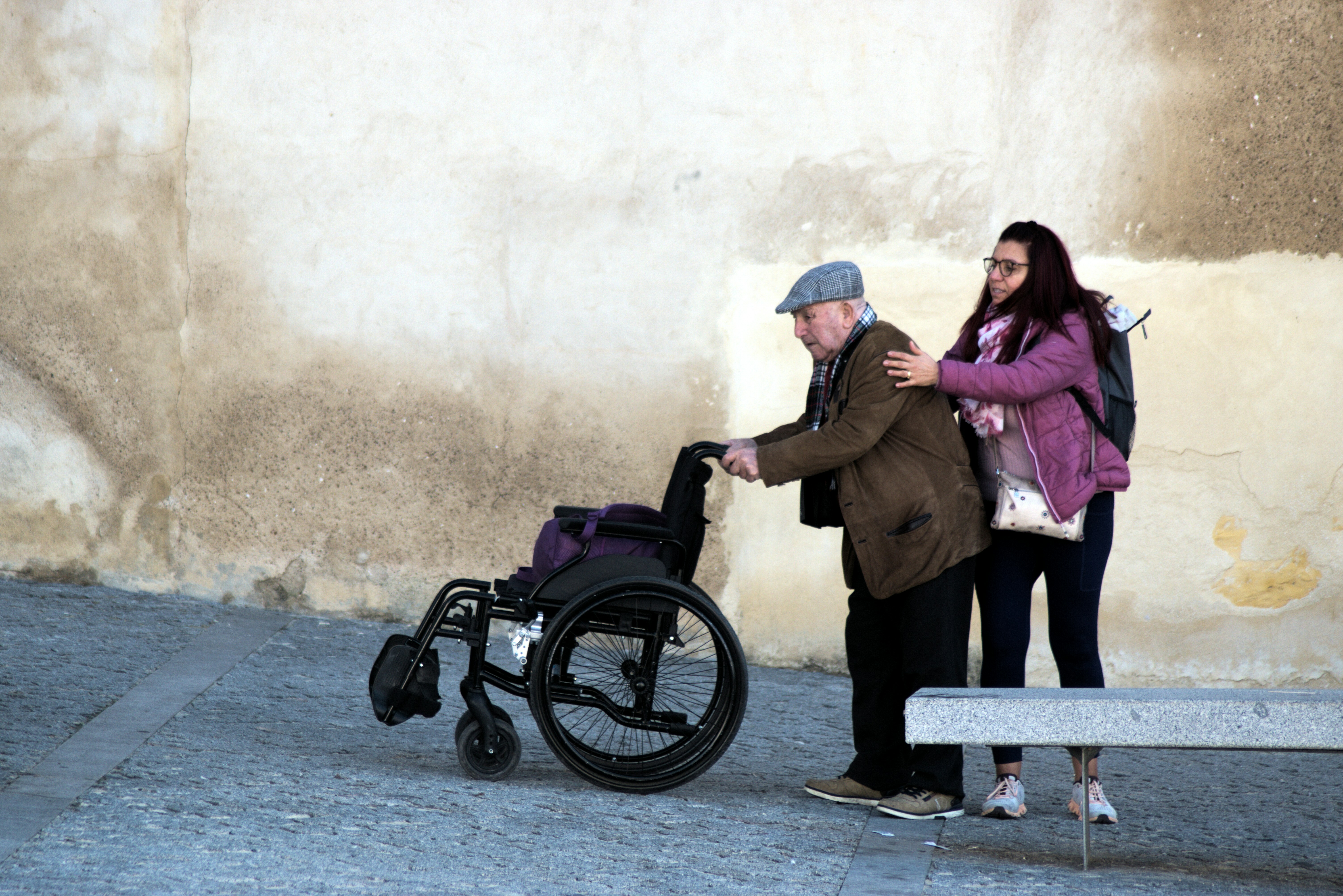 Young woman helps elderly man in wheelchair
