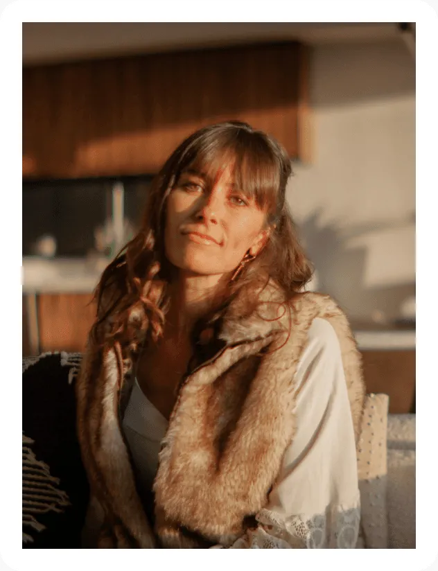 Smiling woman with long brown hair in warm light.