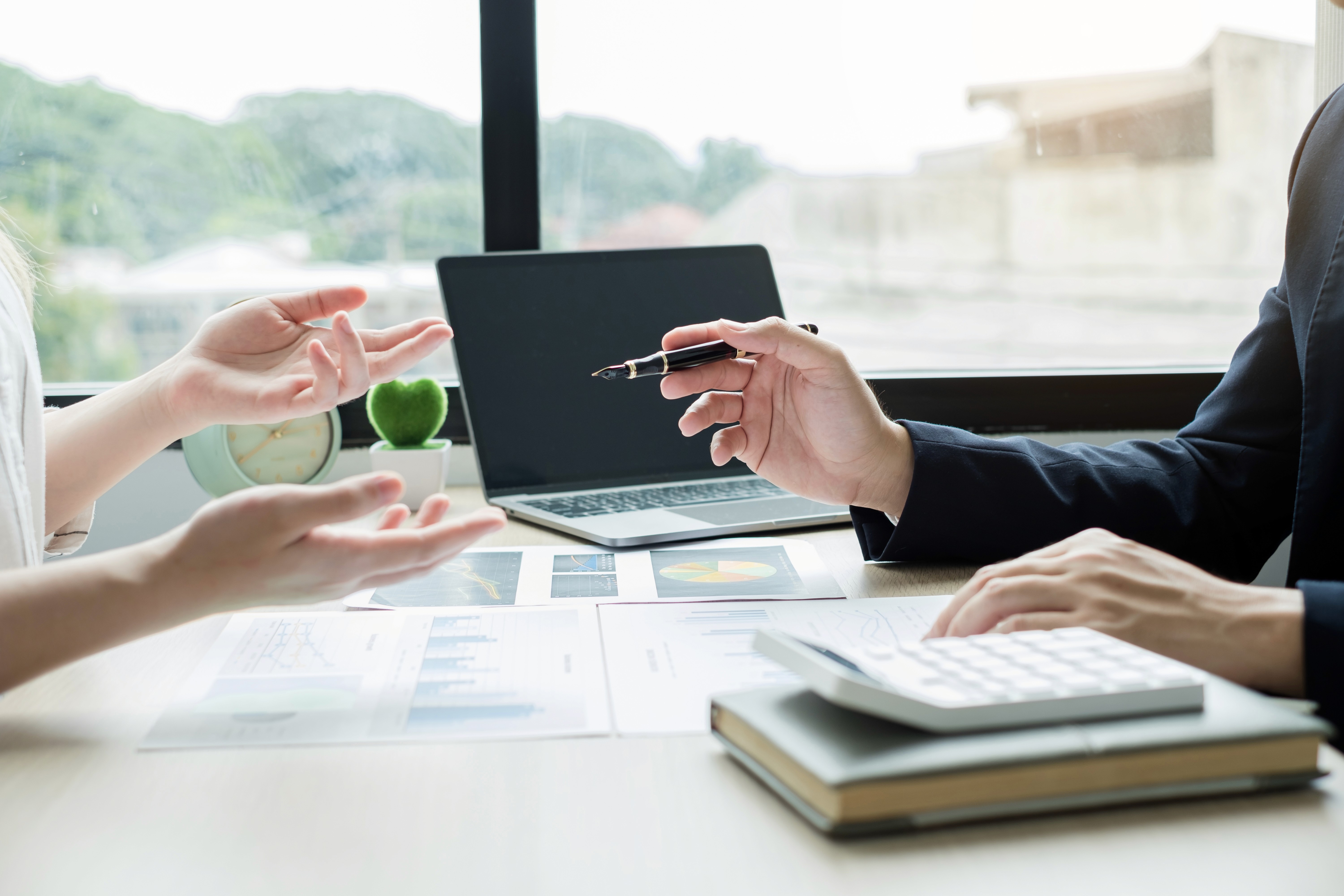 Two stakeholders discussing data across devices, illustrating a business management consultant aligning marketing and finance for better decision-making.