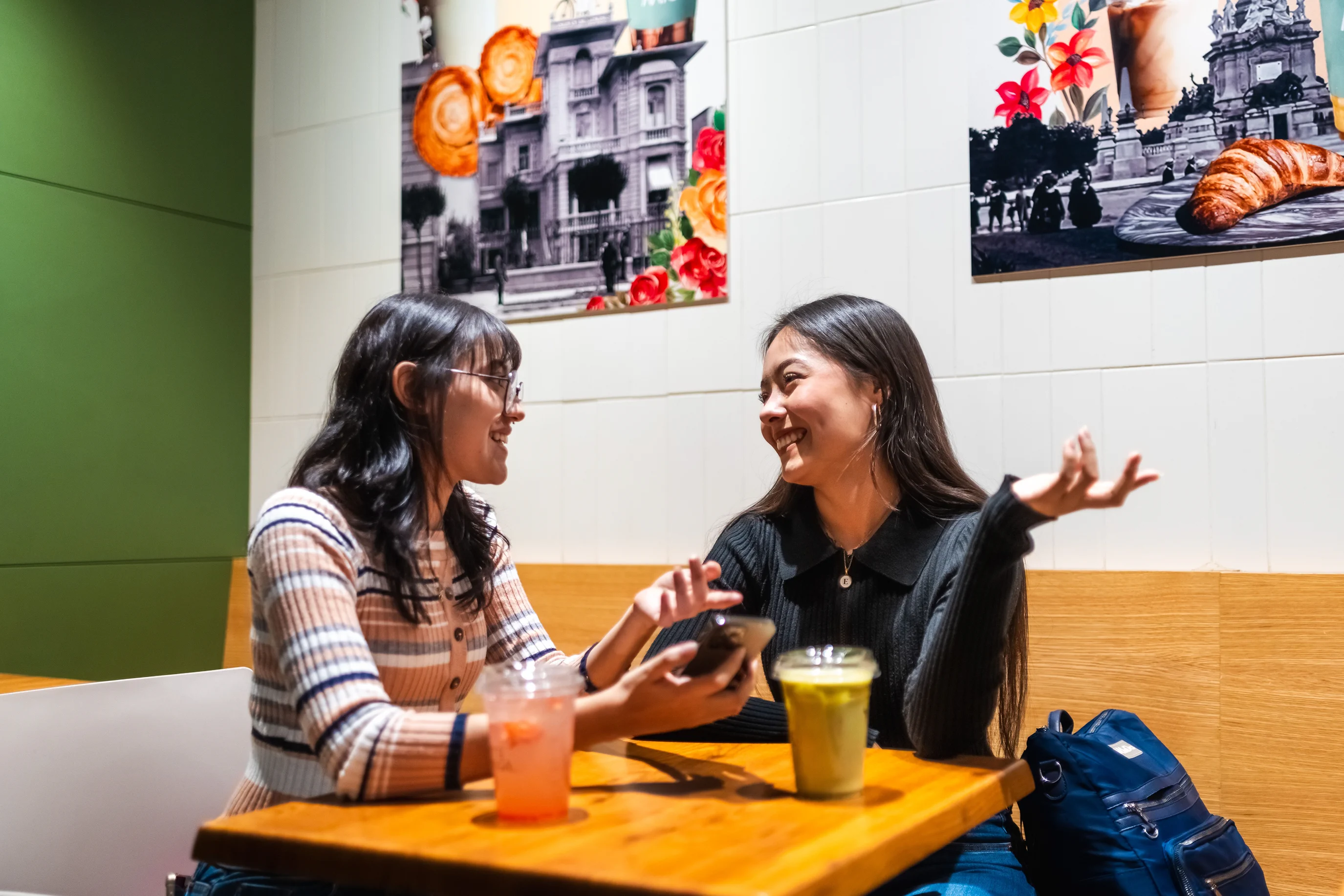 Two women talking over drinks at a cafe table.