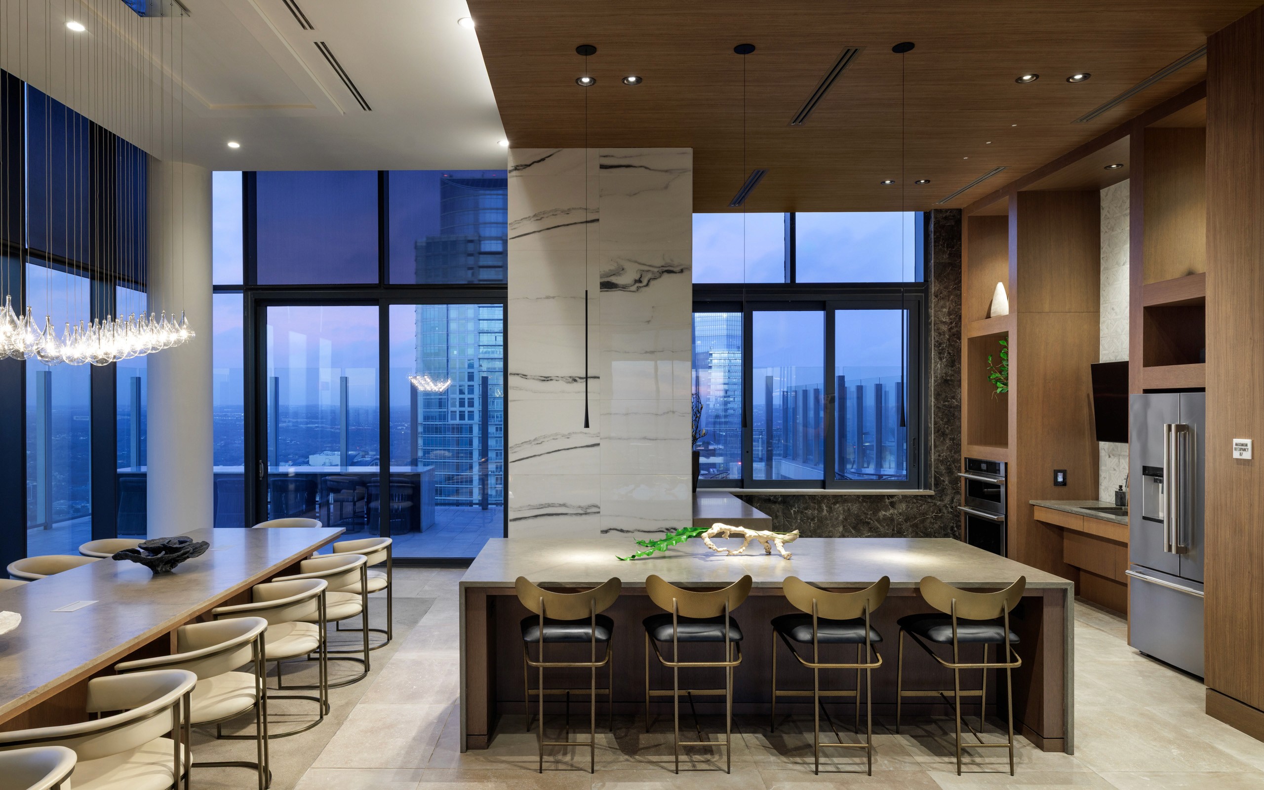 Modern kitchen with island, dining table, and city view.