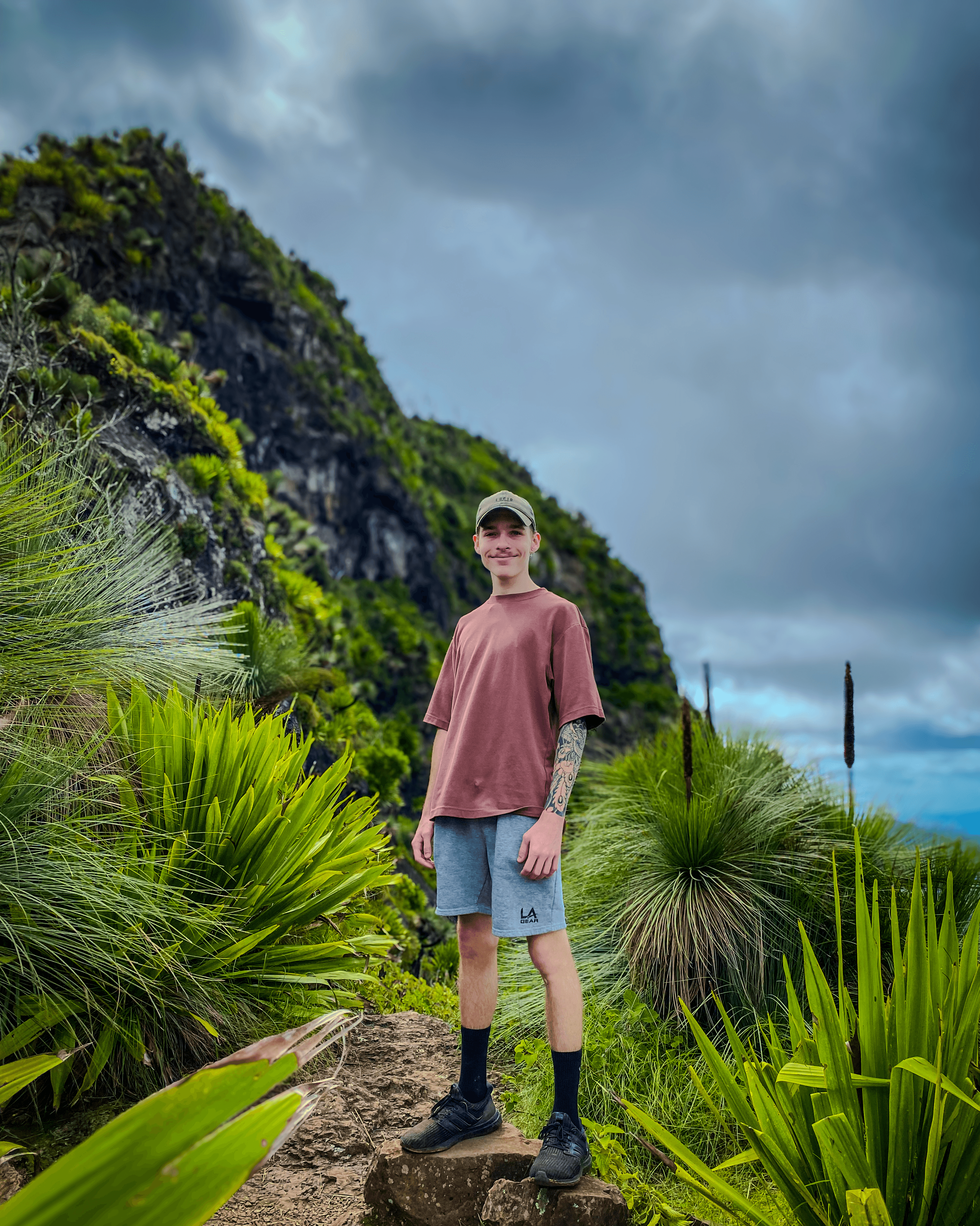 Photo of Dylan Coleman standing on a rock at the top of a mountain, showcasing a moment of achievement and adventure.