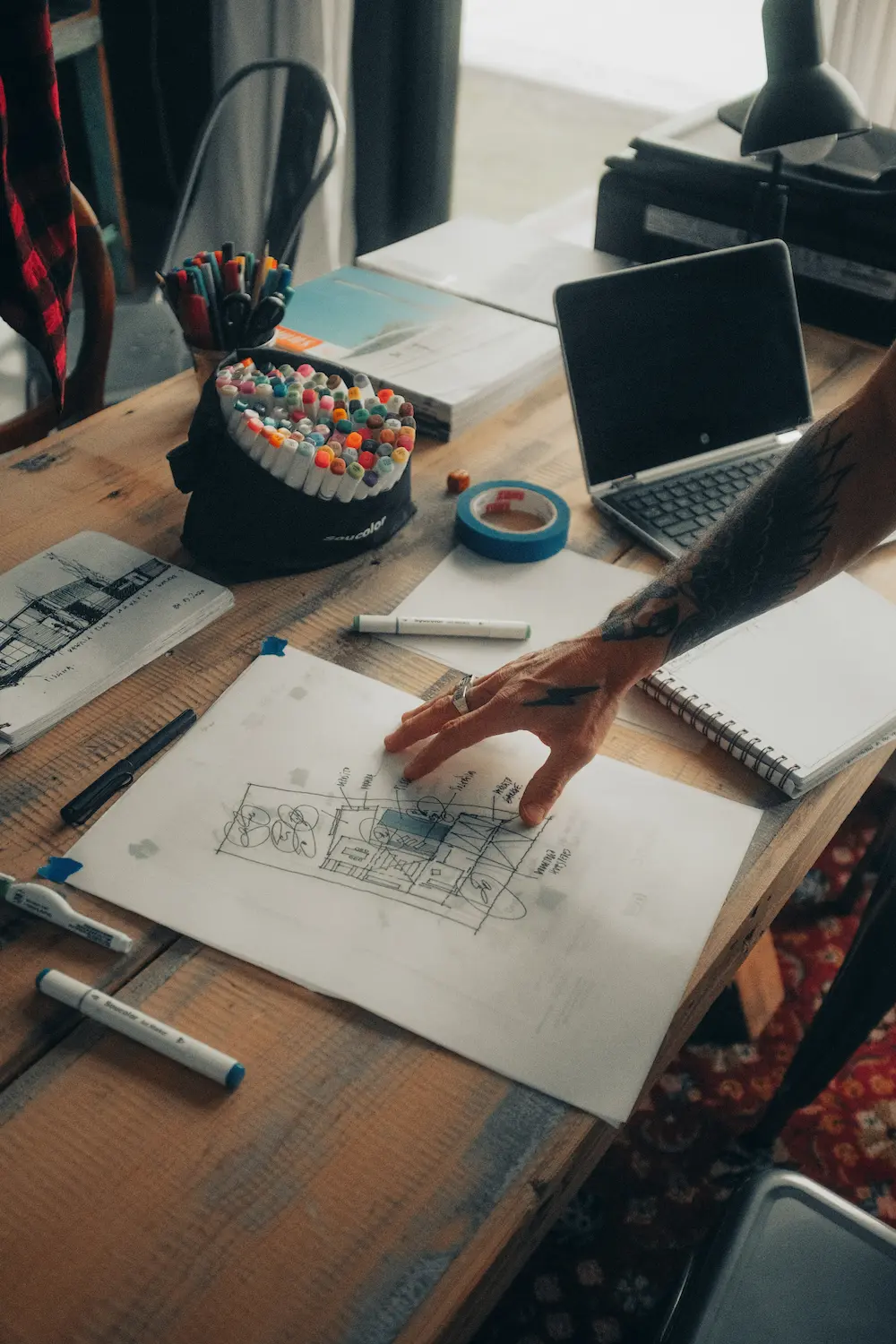 Architect marking up concept floor-plan sketches with markers at a work table