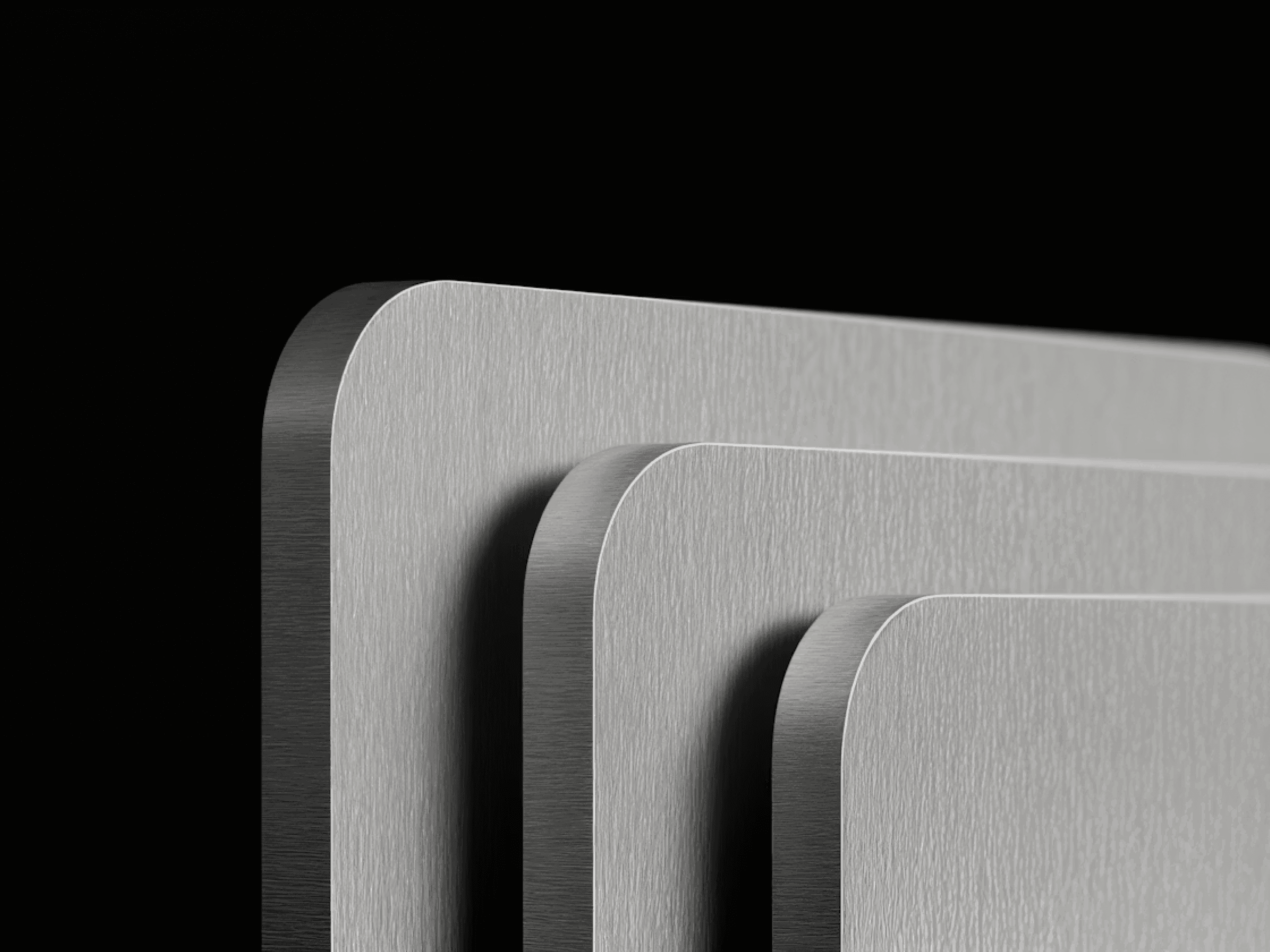 Close-up of overlapping gray metal sheets with rounded corners against black background