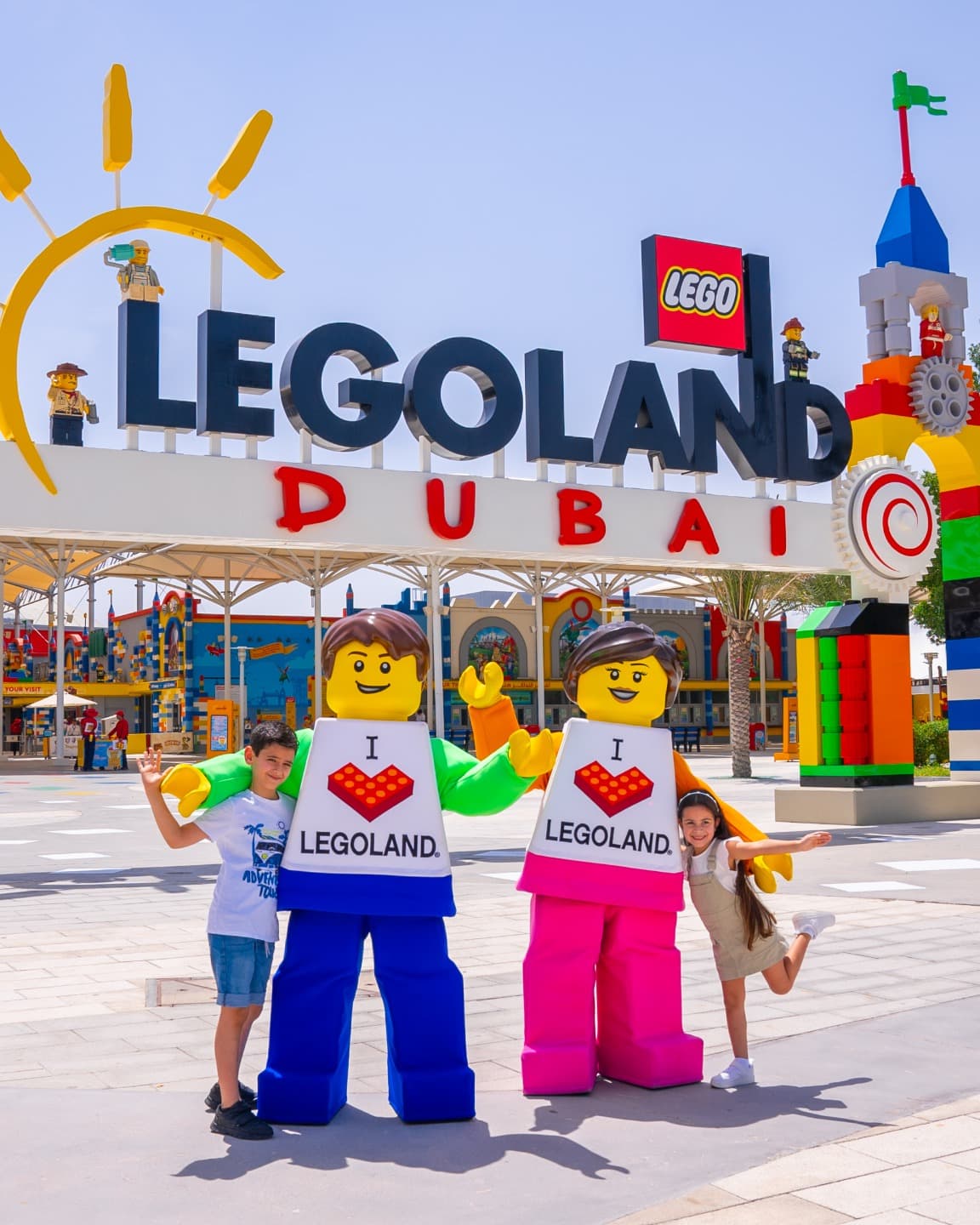Two kids posing next to LEGO structures in front of the Legoland® Dubai signage, part of things to do in Dubai with family.