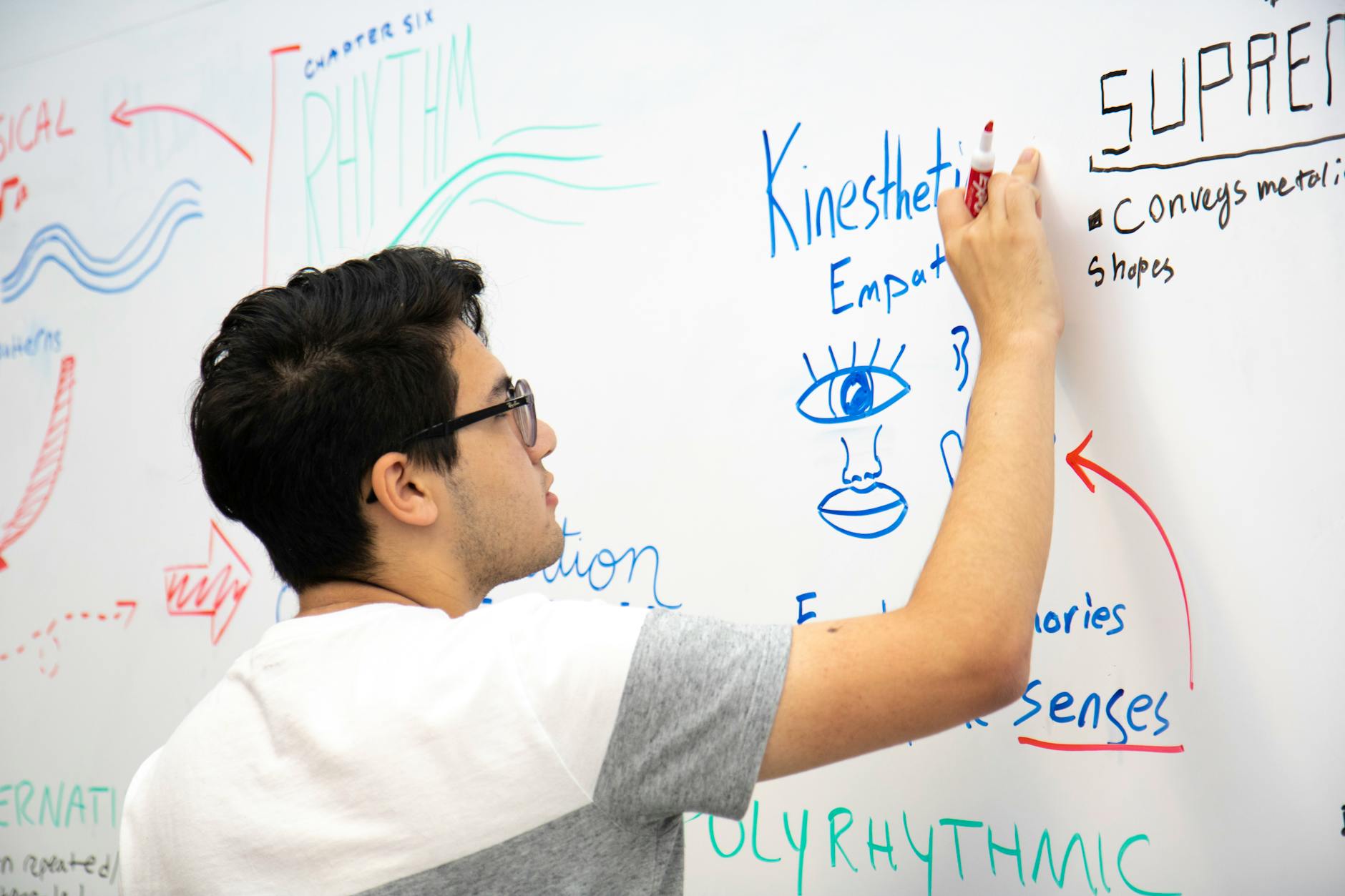 A focused child tapping their pencil and fidgeting with a desktop toy while listening intently to a classroom lecture.